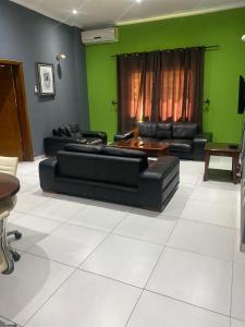 uma sala de estar com sofás pretos e uma parede verde em HOLI FLATS em Accra