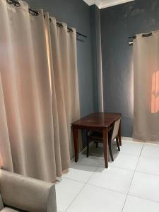 uma mesa e uma cadeira num quarto com cortinas em HOLI FLATS em Accra