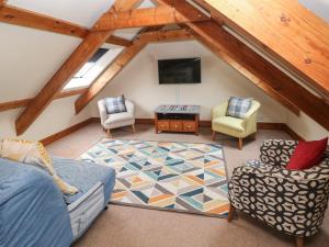 an attic room with a couch and chairs and a tv at Ty Llwyd in Eglwyswrw
