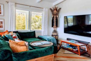 een woonkamer met een groene bank en een tv bij Māla o Kilauea Nature Retreat in Pahoa