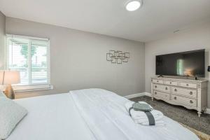 a white bedroom with a large bed and a tv at Fun City Haven Spacious Retreat in Fresno in Fresno