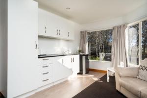 a kitchen with white cabinets and a couch and a window at Country Apartment in Paraparaumu