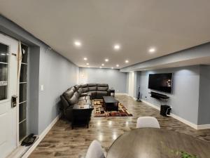 a living room with a couch and a flat screen tv at Adorable 2-Bedoom walkout basement Apartment in Milton