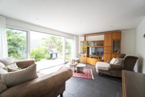 una sala de estar con 2 sofás y una ventana grande en Chasa Emerita Moderne 3,5-Zimmer Terrassenwohnung mit Panoramablick, en Scuol