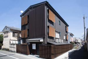 a black building with wooden balconies on a street at Ebisu Ryokan in Kyoto