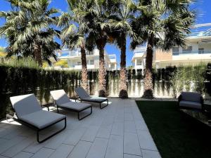 un patio avec des chaises et des palmiers ainsi qu'un bâtiment dans l'établissement Apartamentos Gran Sol con jardin, à Ciudad Quesada