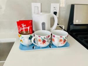 drie koffiekopjes op een aanrecht met een theepot bij Home sweet home in Richmond