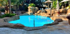a large blue pool with rocks in a backyard at The Red Farm Relais & Spa in LʼInglin