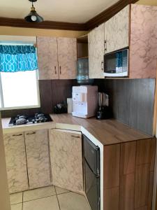 una pequeña cocina con armarios de madera y microondas en Departamento en ecoterra paraiso, en Puerto Vallarta