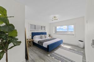 a white bedroom with a blue bed and a window at New DRIFTWOOD SHORES ROAD HOUSE CAMANO in Driftwood Shores