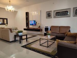 sala de estar con sofás, mesas y TV en Dhana Palace Homestay Gelang Patah en Johor Bahru