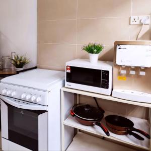 uma cozinha com um micro-ondas e uma frigideira no fogão em Dhana Palace Homestay Gelang Patah em Johor Bahru