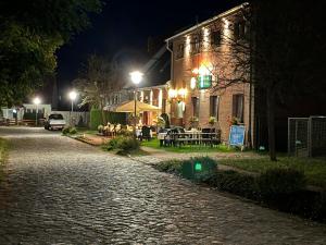 a cobblestone street in front of a building at night at Pension & Gasthof Storchennest in Groß Quassow