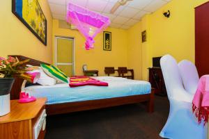 a bedroom with a bed with a pink umbrella hanging from the ceiling at Hotel Kingland in Ruwanwella