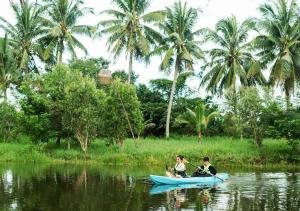 two people in a boat on a river with palm trees at Peam Snea Resort in Kampot