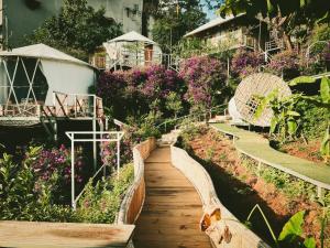 a wooden path through a garden with flowers at Nay Bungalow Dalat in Da Lat