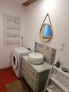 ein Bad mit einem Waschbecken und einem Wandspiegel in der Unterkunft chez Marie et Lulu 
