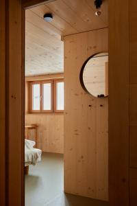 a bedroom with wooden walls and a circular window at Berglodge Goms (Hotel) in Münster