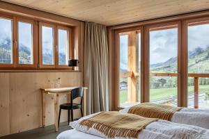 1 Schlafzimmer mit 2 Betten, einem Tisch und Fenstern in der Unterkunft Berglodge Goms (Hotel) in Münster VS