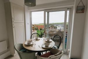 a dining room table with chairs and a large window at LITTLE BLUE HOUSE - Cottage with Seaview near the Lake District National Park in St Bees