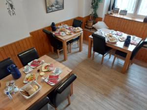 a dining room with two tables and chairs with food on them at Gästehaus Kretschmann in Zeltingen-Rachtig