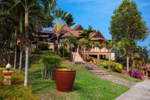 a house with palm trees in front of a yard at The Aiyapura Koh Chang in Ko Chang