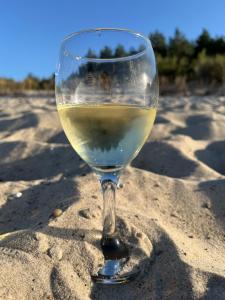 a glass of white wine sitting in the sand at Przy Kolonijnej in Ostrowo
