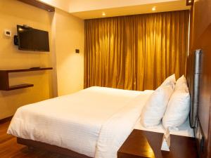 a hotel room with a white bed and a window at Classic Sarovar Portico Trivandrum in Trivandrum