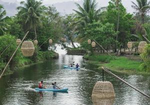 a group of people are canoeing down a river at Peam Snea Resort in Kampot