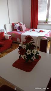 uma sala de estar com uma mesa com um arranjo de flores em Apartman Mira em Pozarevac