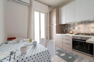 een keuken met een tafel met witte stoelen en een keuken met witte kasten bij Casa Lido Venezia with balconies LOC09394 in Venetië-Lido