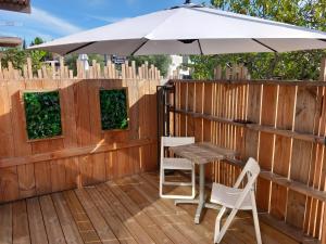 einen Tisch, zwei Stühle und einen Regenschirm auf einer Terrasse in der Unterkunft Location Studio indépendant avec terrasse ,les vignes d'élian in Saint-Médard-en-Jalles