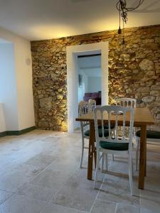 a dining room with a stone wall and a table and chairs at La Petite Fenêtre in Casale Marittimo