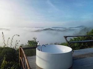 uma banheira sentada num deque com vista para as nuvens em Papa Garden Khaokho em Khao Kho