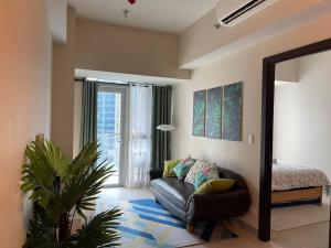 ein Wohnzimmer mit einem Sofa und einem Spiegel in der Unterkunft Tropical 1BR Uptown Parksuites BGC, 200mbps Smart TV in Manila