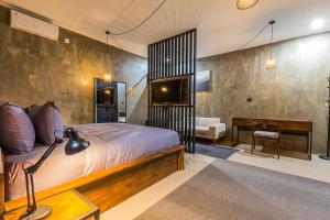 a bedroom with a bed and a tv and a desk at Modern Industrial Apartment-Umalas w Wifi and pool in Canggu