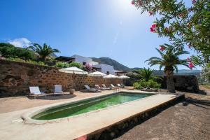 a swimming pool with chairs and a stone wall at Il Mulino di Scauri in Pantelleria