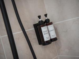 two bottles of soap sitting on a wall in a shower at Le Lotus - Parking public gratuit, wifi haut débit, proche autoroute, gare & centre ville in Mâcon