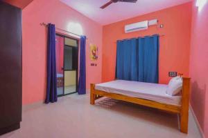 1 dormitorio con 1 cama con cortinas azules y paredes de color naranja en Indira Homestay en Mangalore