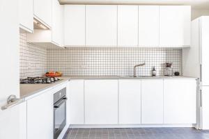 una cocina blanca con armarios blancos y fregadero en Gorgeous 1BD Balearic-style home with Gardens en Cheltenham