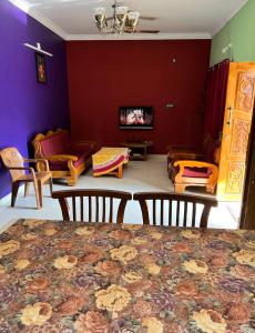 sala de estar con paredes de color púrpura, mesa y sillas en Indira Homestay en Mangalore