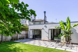 una casa blanca con un patio con césped verde en Gorgeous 1BD Balearic-style home with Gardens en Cheltenham