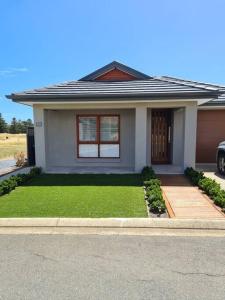 a small house with a lawn in front of it at Coastal Palms - relax by the golf course in Normanville