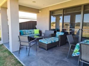 a patio with a couch and chairs and a table at Coastal Palms - relax by the golf course in Normanville
