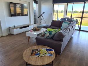a living room with a couch and a table at Coastal Palms - relax by the golf course in Normanville