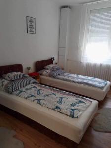 two beds sitting in a room with a window at Átutazó Apartman in Nyíregyháza
