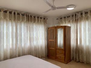 a bedroom with a bed and a cabinet and curtains at One Cozy Bedroom in a shared apartment in Kumasi