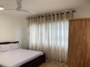 um quarto com uma cama e uma janela com cortinas em One Cozy Bedroom in a shared apartment em Kumasi