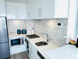 uma cozinha branca com um lavatório e um frigorífico em Modern Gold Coast Apartment with great Amenities em Gold Coast