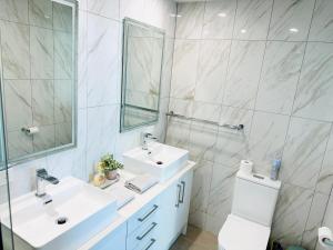 uma casa de banho branca com 2 lavatórios e um espelho em Modern Gold Coast Apartment with great Amenities em Gold Coast